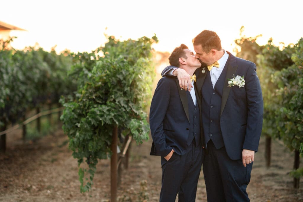 grooms kissing during sunset