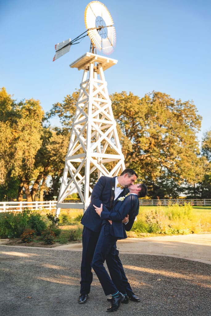 gay couple kissing in front of windmill