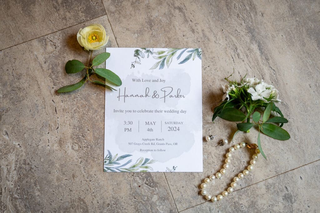 Flat lay image of wedding accessories, including invite, flowers, and jewelry