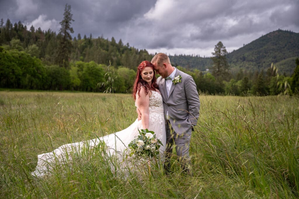 bride and groom standing in a field touching foreheads